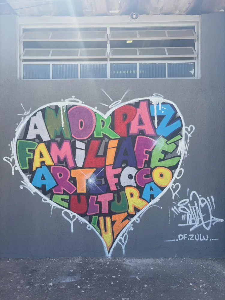 Coração com palavras coloridas pintado na parede abaixo de uma janela